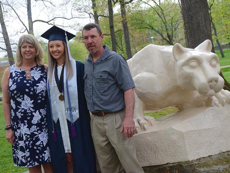 A recent graduate posing with her parents